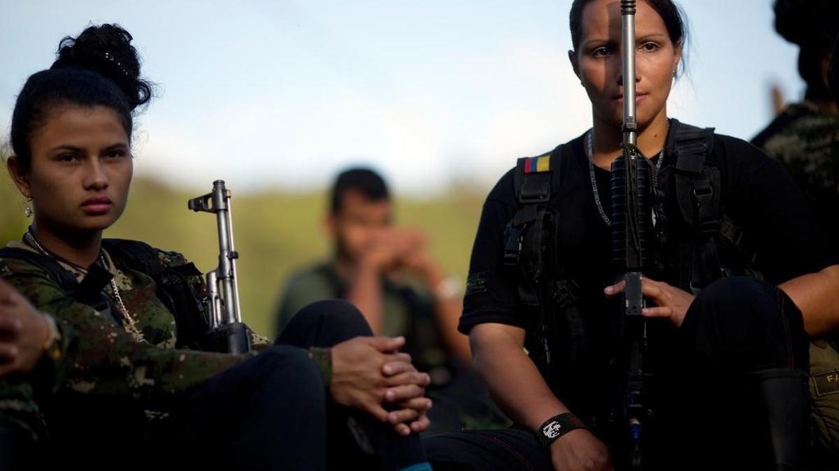 In this Jan. 4, 2016, file photo, Juliana, 20, left, and Mariana, 24, rebel soldiers for the 36th Front of the Revolutionary Armed Forces of Colombia, or FARC, listen to a commander speak on the peace negotiations between the rebels and the Colombian government.
