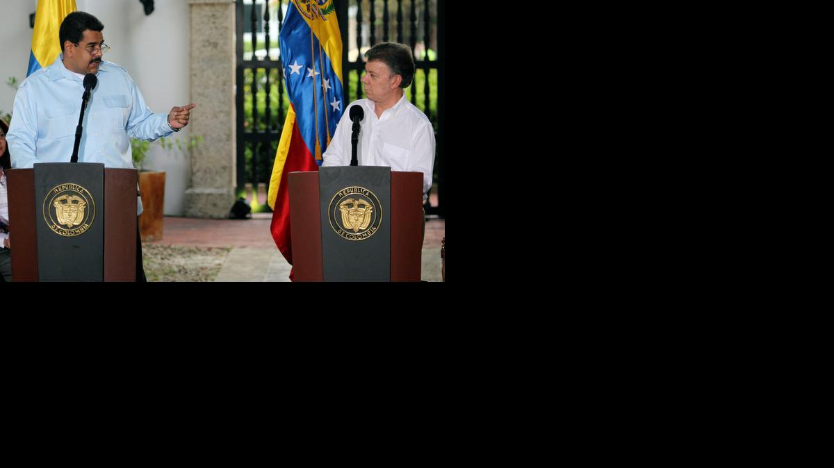 
FILE - In this Aug. 1, 2014 file photo, Venezuela's President Nicolas Maduro points towards Colombia's President Juan Manuel Santos during a joint press conference after a bilateral meeting in Cartagena, Colombia. Santos has been trying to repair commercial ties to Venezuela. Trade between the neighbors had fallen by 70 percent in recent years amid sour relations as Santos' predecessor, Alvaro Uribe, bucked the regional trend by vocally criticizing the late Venezuelan President Hugo Chavez. 
