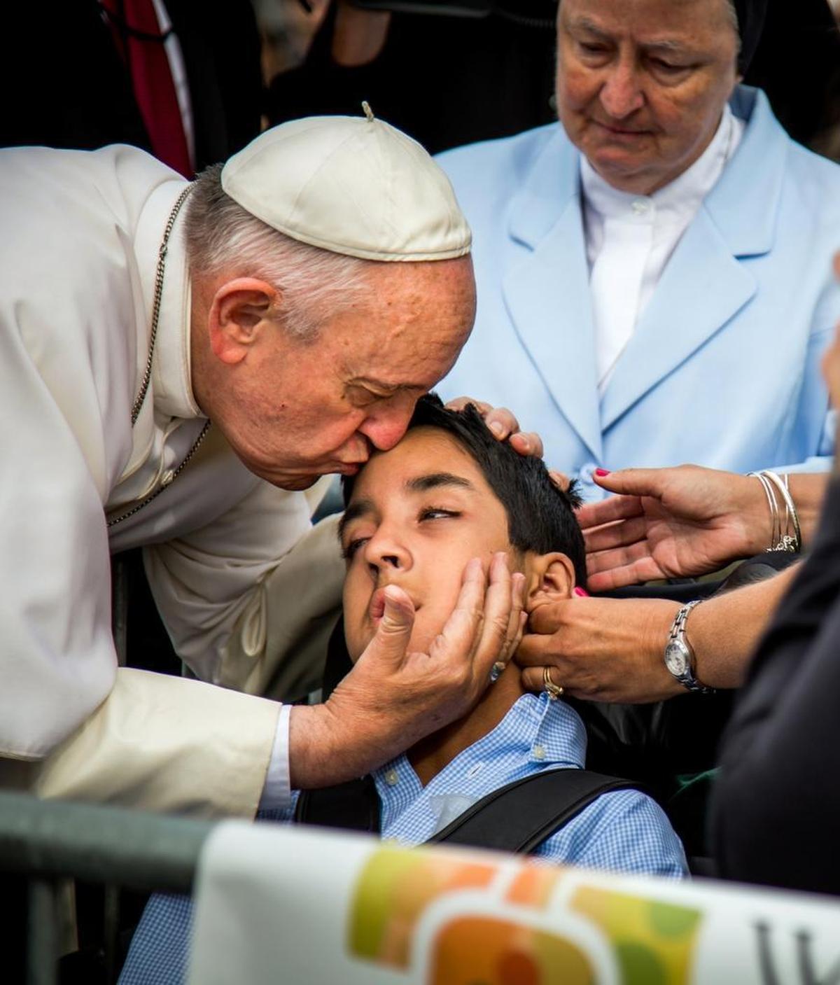 In this photo provided by World Meeting of Families, Pope Francis kisses and blesses Michael Keating, 10, of Elverson, Pa after arriving in Philadelphia and exiting his car when he saw the boy, Saturday, Sept. 26, 2015, at Philadelphia International Airport. Keating has cerebral palsy and is the son of Chuck Keating, director of the Bishop Shanahan High School band that performed at Pope Francis' airport arrival.