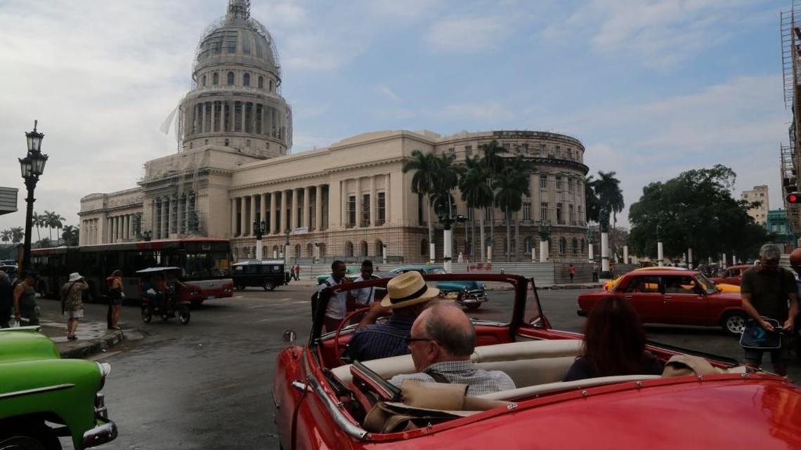 Tourists set off for a spin in a classic American convertible car backdropped by Havana’s Capitolio building.