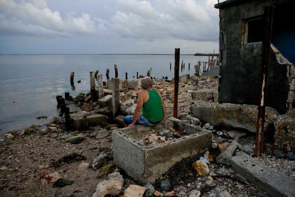 A man looks out to sea as he sits on the remains of a restaurant destroyed by Hurricane Irma in Isabela de Sagua, on Sept. 12, 2017. The powerful storm ripped roofs off houses, collapsed buildings and flooded the coastline after cutting a trail of destruction across the Caribbean.