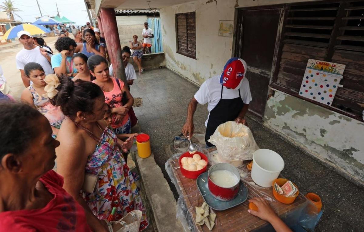 A long line of Cojímar residents, in search of a cool treat, wait to buy orange-pineapple ice cream being scooped from a bucket for the equivalent of about four cents a scoop.