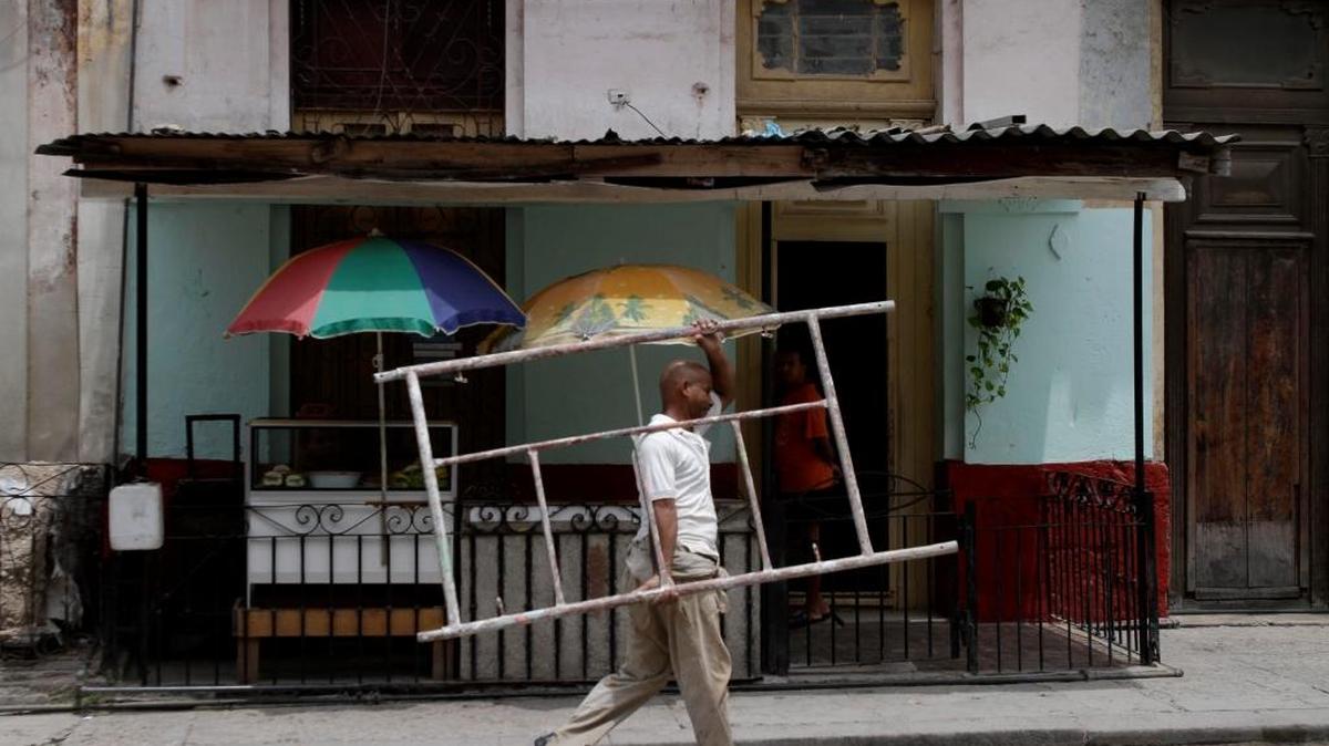 In This file photo Ruben Font carries a scaffold piece to his home in Havana, Cuba.