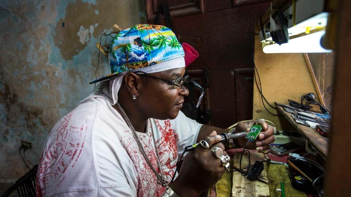 Private jeweler and electronics technician Gabriel La O repairs a mobile phone inside a government store where he rents work space in Havana, Cuba.