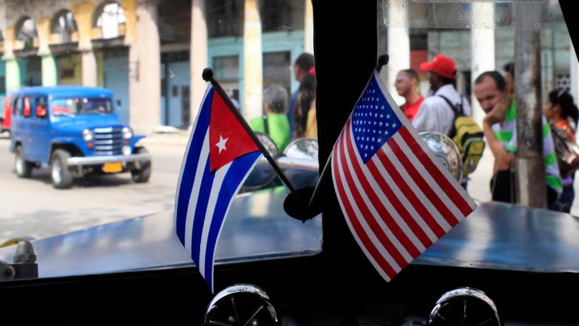 In this March 22, 2013 file photo, miniature flags representing Cuba and the U.S. are displayed on the dash of a classic American car in Havana, Cuba.