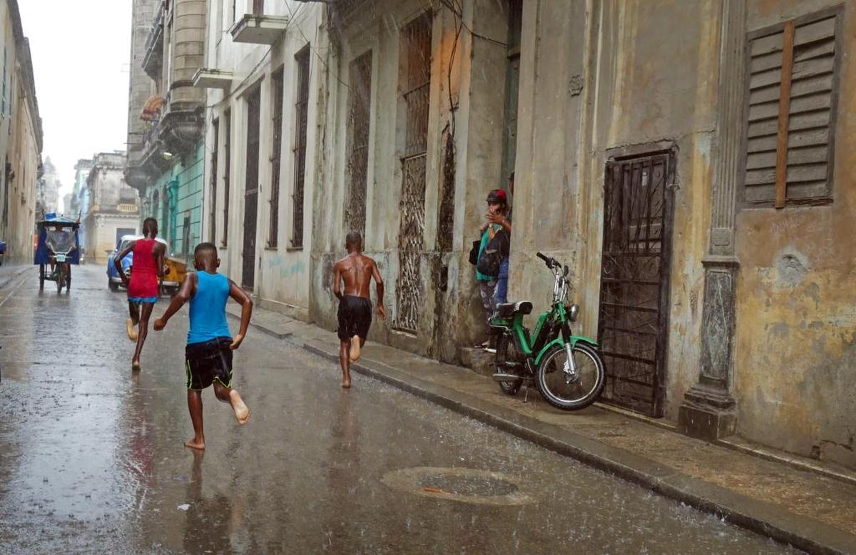 Young boys run through a downpour in Old Havana.