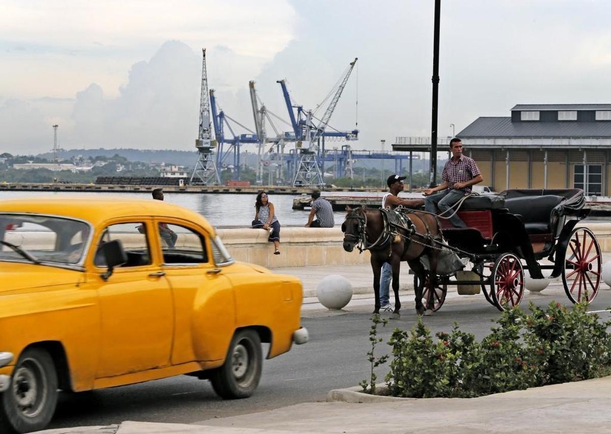 A vintage car and horse-drawn carriage on a road along the Port of Havana, Cuba on Friday, Sept. 18, 2015.