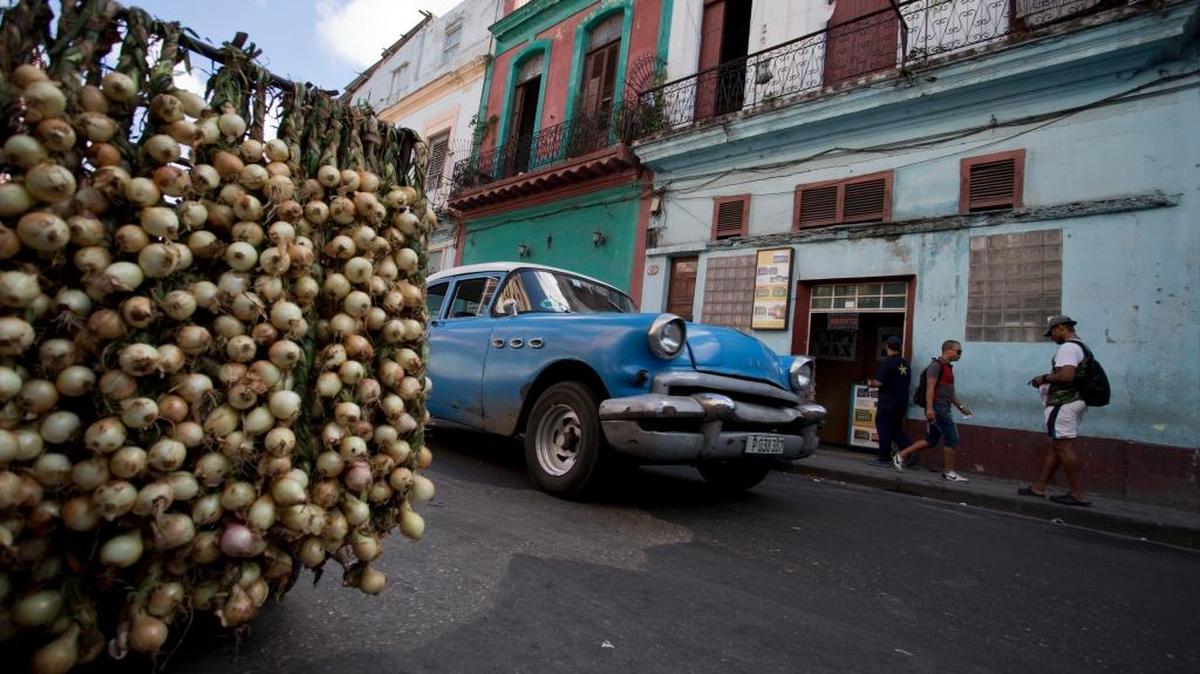 A classic American car passes by a stall selling onions in Havana, Cuba in 2014.