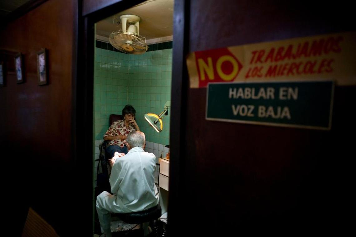 In this June. 8, 2017 photo, podiatrist Serafin Barca, 80, attends a patient in his clinic in Havana, Cuba. Only a handful of private practitioners like Barca remain because no new ones have been allowed in more than half a century.