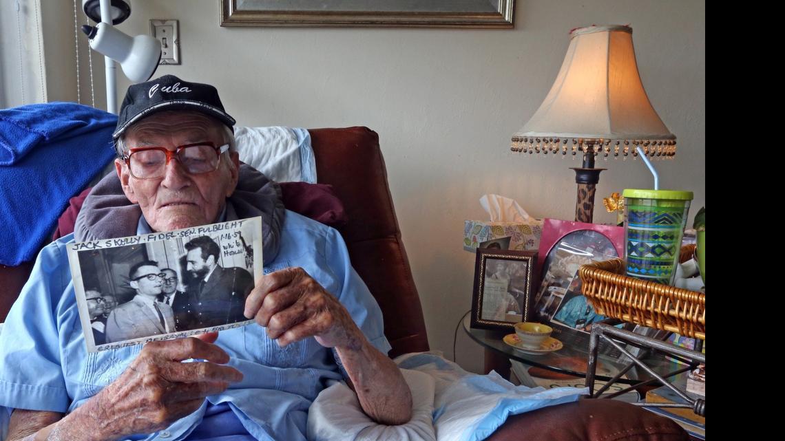 
John Skelly reads the writing on the back of a photograph of himself and Fidel Castro in 1959 Havana. Skelly grew up in Banes, Cuba, where his father ran the railroad for United Fruit. His neighbors were the Diaz-Balarts. As a newsman, he was there when Fidel Castro marched triumphant into Havana and he briefly served as Fidel's press secretary. June 3, 2015.
