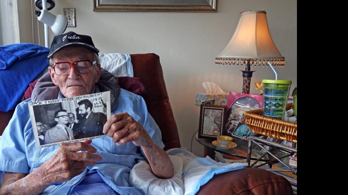 
John Skelly reads the writing on the back of a photograph of himself and Fidel Castro in 1959 Havana. Skelly grew up in Banes, Cuba, where his father ran the railroad for United Fruit. His neighbors were the Diaz-Balarts. As a newsman, he was there when Fidel Castro marched triumphant into Havana and he briefly served as Fidel's press secretary. June 3, 2015.
