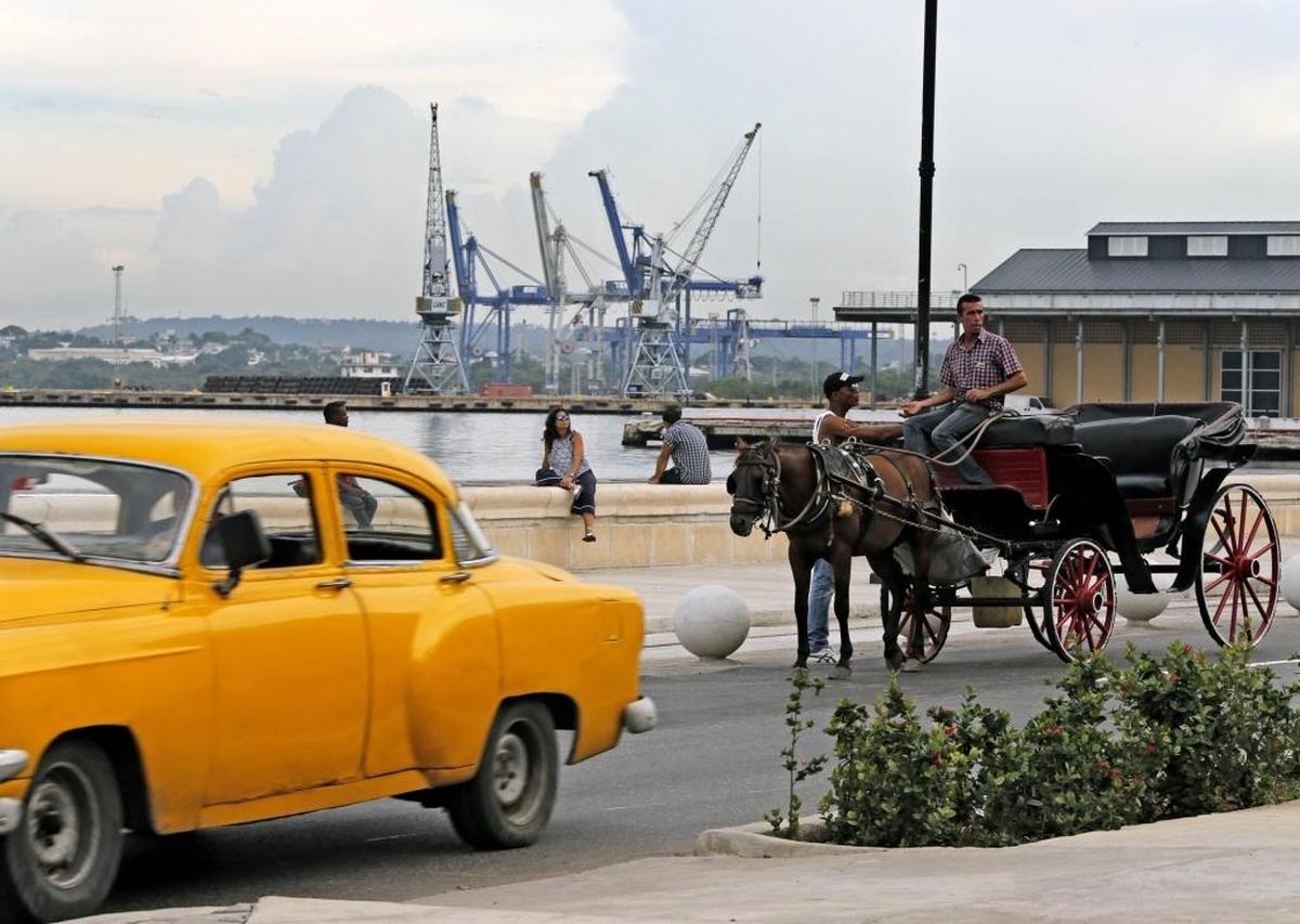 A vintage car and horse-drawn carriage on a road along the Port of Havana, Cuba on Friday, Sept. 18, 2015.