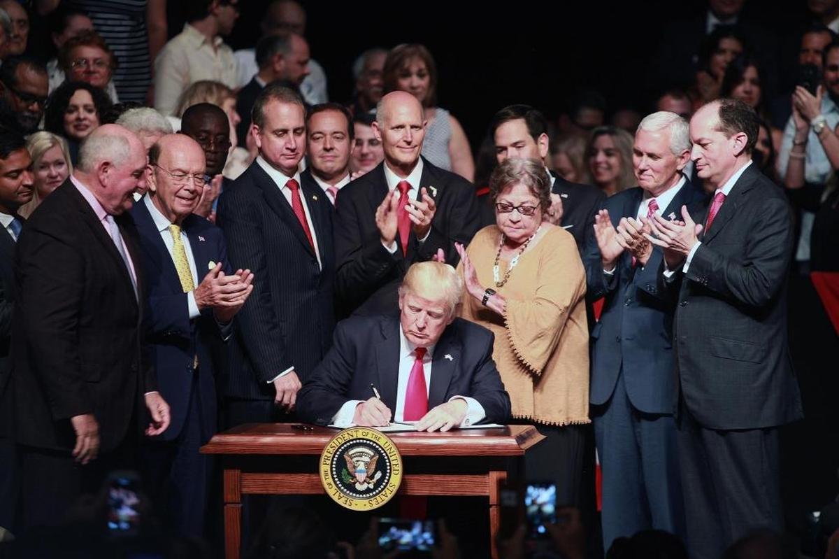 President Donald Trump, surrounded by Cuban Americans and Vice President Mike Pence, signs a document outlining his new Cuba policy after a speech at the Manuel Artime Theater in Little Havana on June 16, 2017.