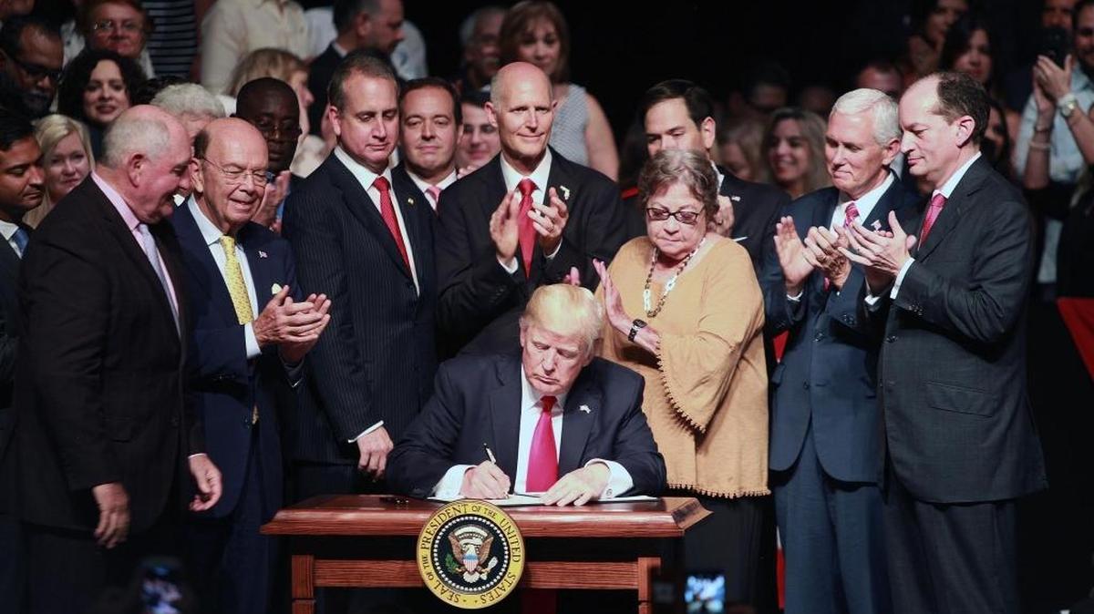 President Donald Trump, surrounded by Cuban Americans and Vice President Mike Pence, signs a document outlining his new Cuba policy after a speech at the Manuel Artime Theater in Little Havana on June 16, 2017.