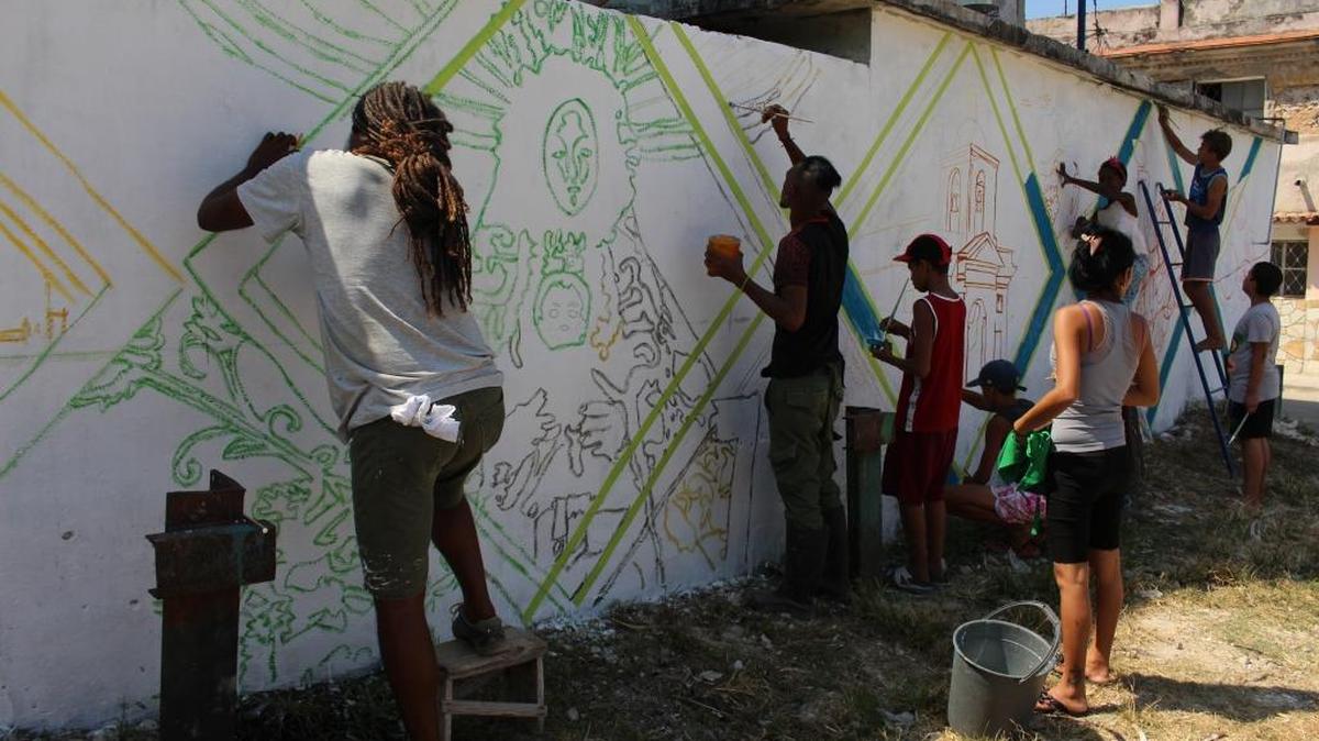 U.S. muralist Michelle Angela Ortiz paints a mural in Regla, Havana, with local artists and members of the community.