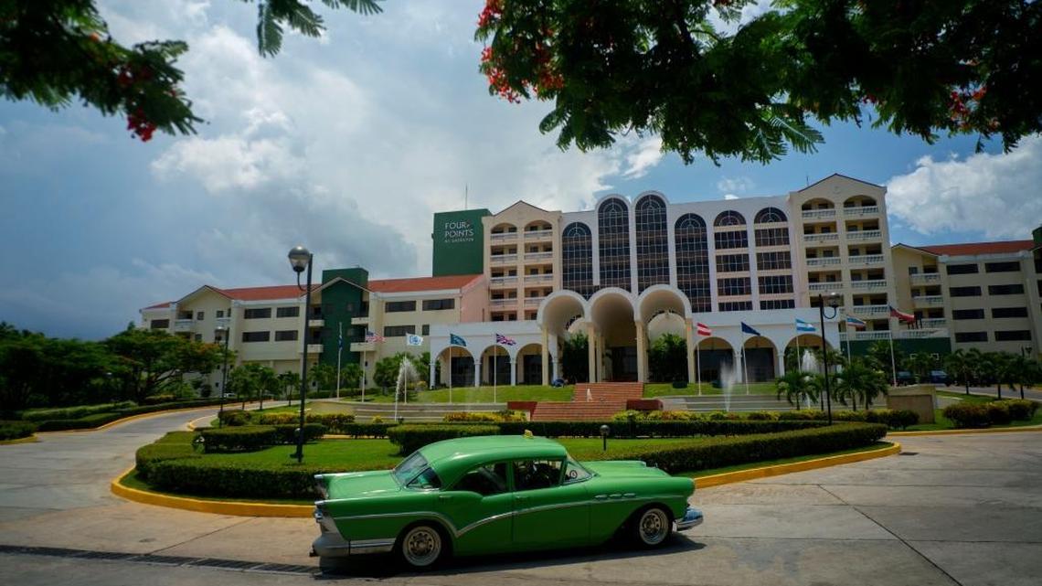 In this June 28, 2016 file photo, a vintage car passes in front of the Four Points by Sheraton hotel in Havana, Cuba, managed vy the U.S.-based Starwood hotel chain and owned by Gaviota, part of the military conglomerate known as GAESA.
