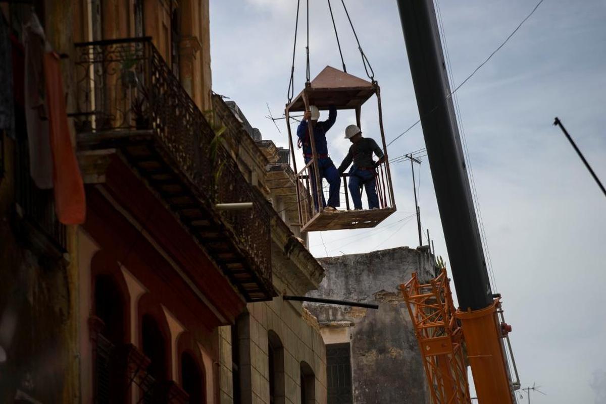 Workers in a metal box, hanging from a crane, remove the wall of a building that collapsed in Old Havana on July 16, 2015. Cuban officials say four people died in the Wednesday collapse, and a government statement published in Communist Party daily Granma said the two-story residence contained two family homes.