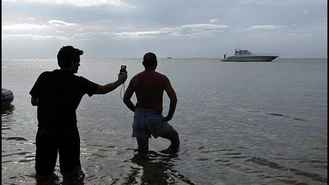 Cinematographer Brian Hubbard, measures the light as actor Jorge Luis Alvarez, prepares for a scene on Biscayne Bay during the filming of the short movie “Wet Foot/Dry Foot, the story of two rafters.