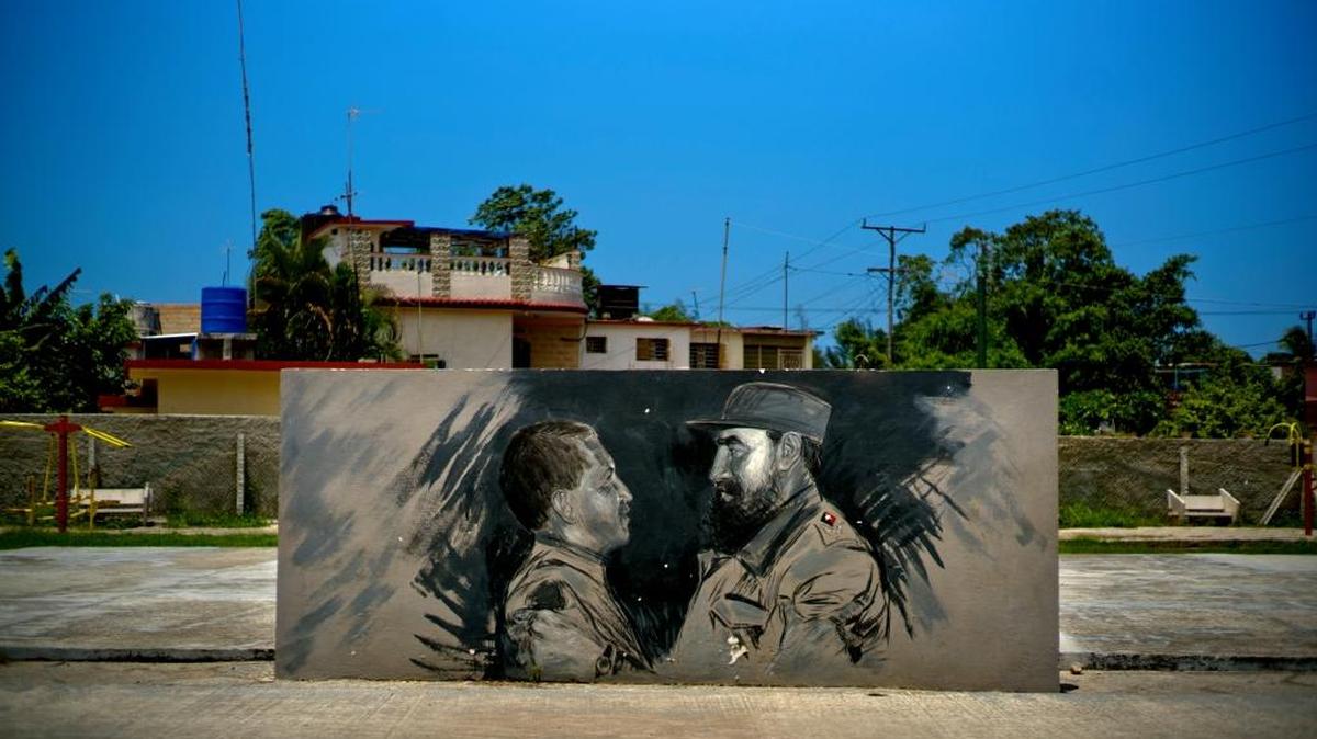 A painting inspired by a 1994 photo taken by Cuban photojournalist Ismael Francisco showing Cuba's Fidel Castro, right, welcoming Venezuela's Hugo Chávez before he became president years later, at the Havana airport, covers a wall separating recreation spaces at a park in Havana, Cuba, Sunday, Aug. 13, 2017.