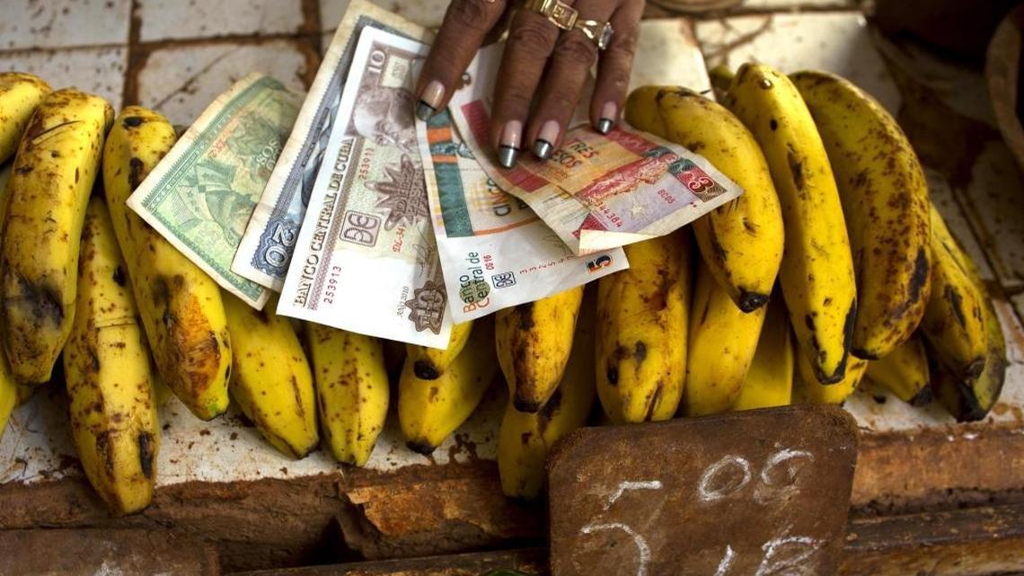 In this file photo, a food vendor spreads out convertible pesos, known as CUCs, the two bills on the right, and regular Cuban pesos at her stand in a vegetable market in Havana, Cuba.
