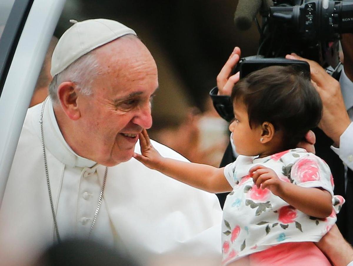 An unidentified child, who was carried out from the crowd to meet Pope Francis, reaches out to touch the Pontiff's face during a parade on his way to celebrate Sunday Mass on the Benjamin Franklin Parkway in Philadelphia, Sunday, Sept. 27, 2015. Pope Francis is in Philadelphia for the last leg of his six-day visit to the United States. 