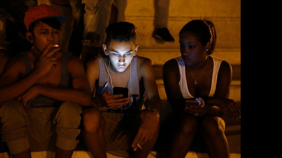 
To be young and connected: Cuba young people use a password protected Wi-FI network from a nearby five-star hotel to surf the Internet on their Smartphones in downtown Havana. Cubans are hungry for better Internet connections.
