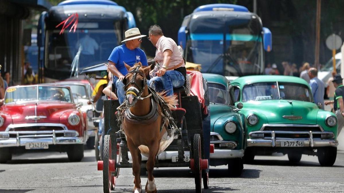 Tourist buses share the road along with vintage American cars and a horse drawn buggy in Havana, Cuba. Travel to Cuba is still legal for American travelers, but there are new rules.