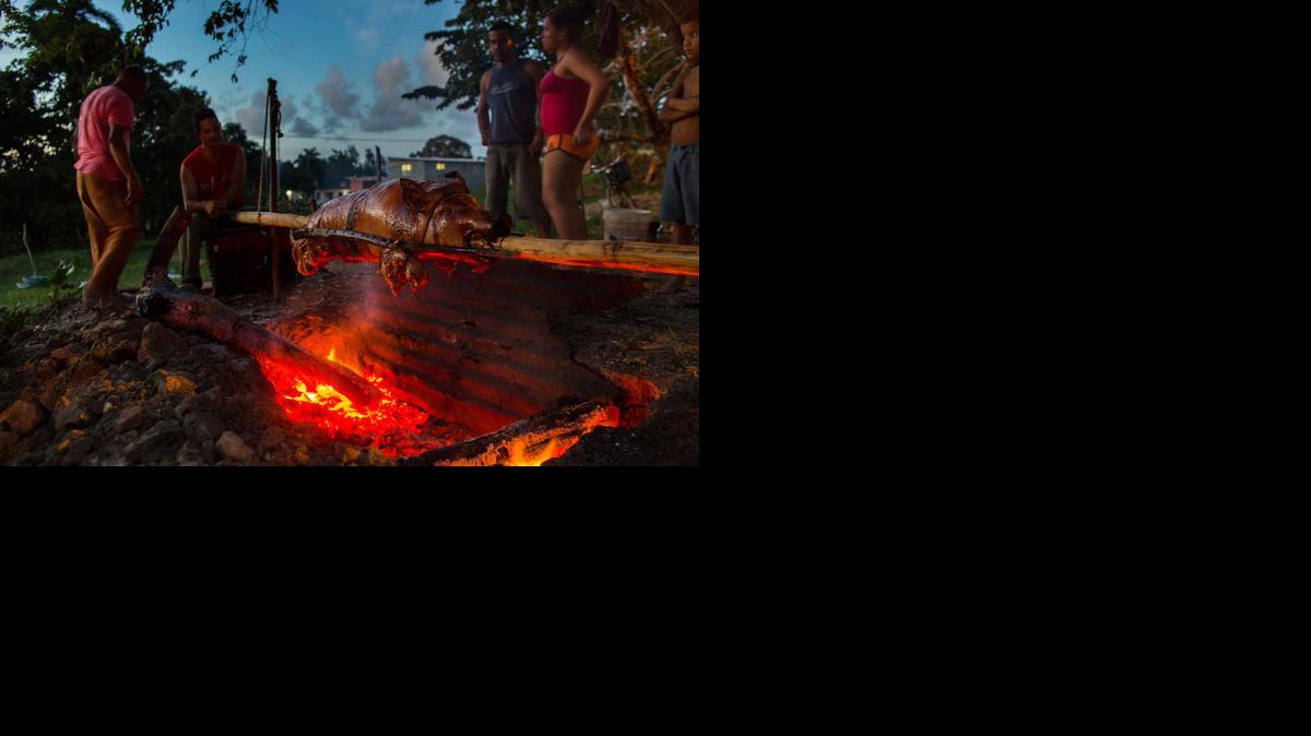 
Several members of the Rodriguez Osorio family stand next to a slow roasted pig that is being cooked over a charcoal fire for the New Year’s Eve dinner, at sunset in Campo Florido, east of Havana, Cuba, The dish known as “Cerdo en Pua” or pig on a stick, is a New Year’s Eve tradition and delicacy that Cuban families enjoy during the last night of the year.
