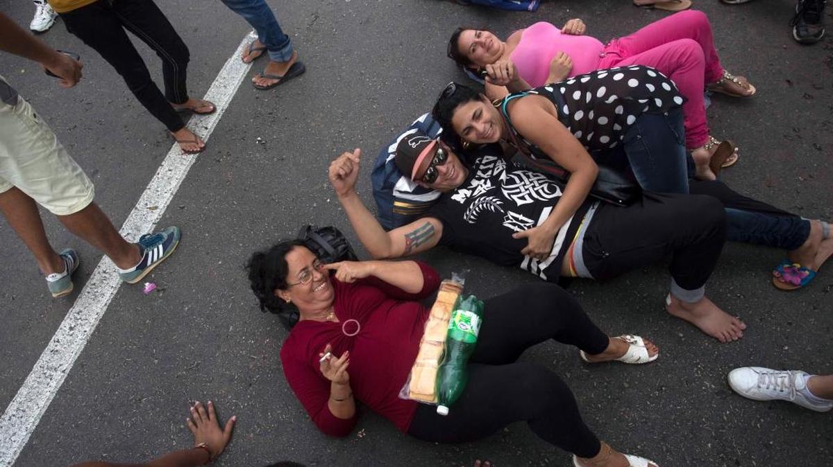 Cubans interrupt traffic in a lie-down protest on Havana’s Fifth Avenue near Ecuador's embassy to express discontent with a new rule that requires Cubans to e a visa to visit the South American country, Saturday, Nov. 28, 2015.