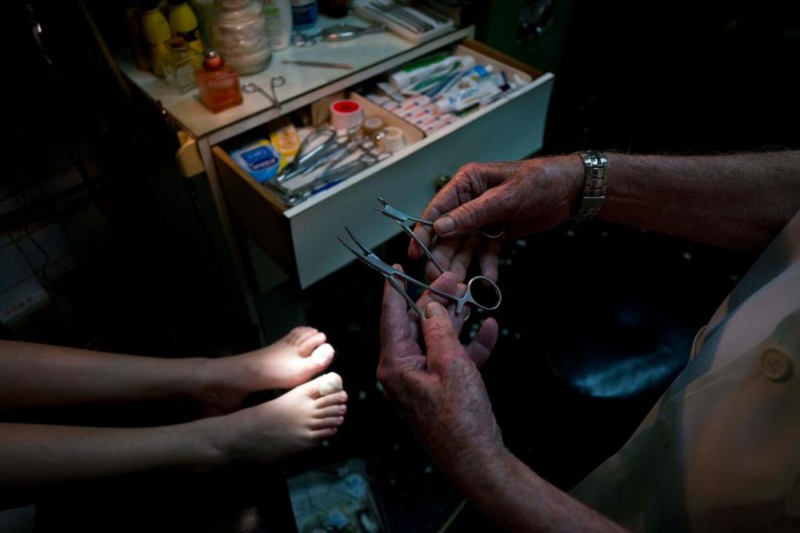 In this June. 8, 2017 photo, podiatrist Serafin Barca attends a patient in his clinic in Havana, Cuba. Barca is busy from morning 'til night treating patients frustrated with the inefficiency of the state system. "The service is of higher quality," Barca said. "If you get a patient and you don't treat them well ... you don't get them back."