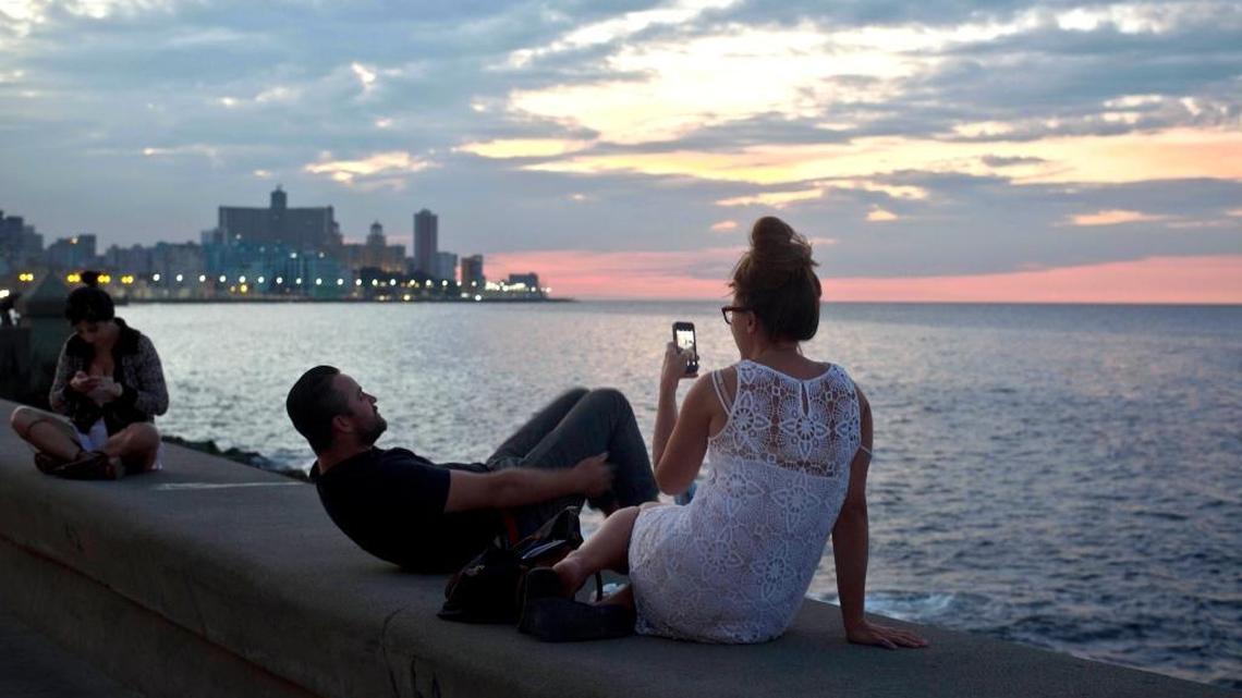 This Dec. 19, 2014 file photo shows tourists taking photos along the waterfront promenade known as the Malecon in Havana.