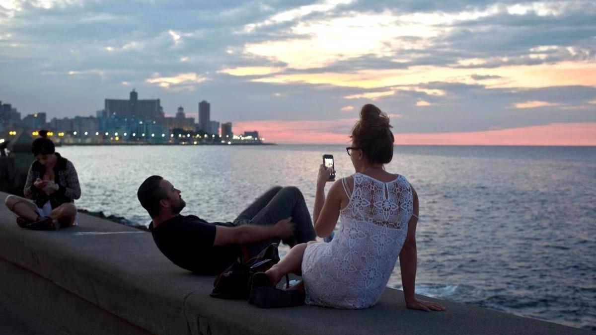 This Dec. 19, 2014 file photo shows tourists taking photos along the waterfront promenade known as the Malecon in Havana.