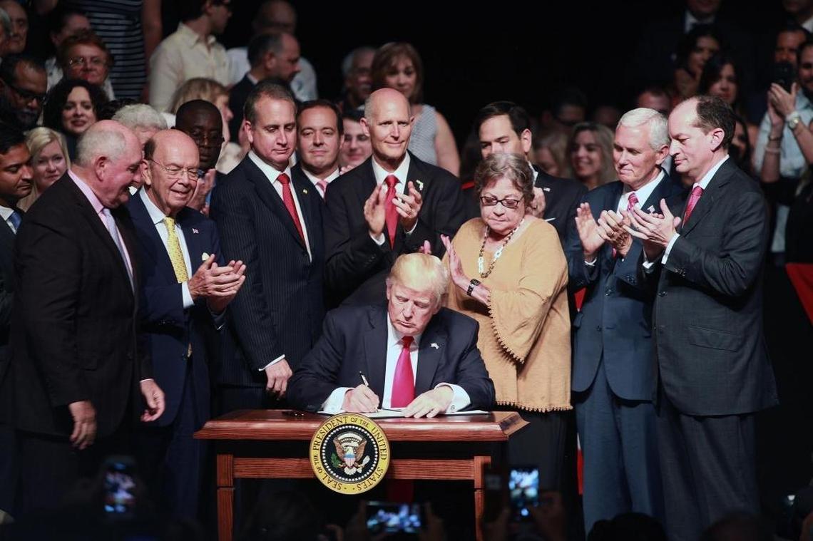 President Donald Trump signs a memorandum on strengthening Cuba surrounded by Cuban Americans and Vice President Mike Pence at the Manuel Artime Theater in Little Havana.