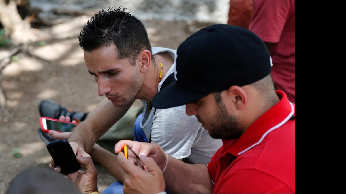 
Internet users go online with their smartphones using the first public Wi-Fi hotspot in Havana, Cuba on Thursday, July 2, 2015.

