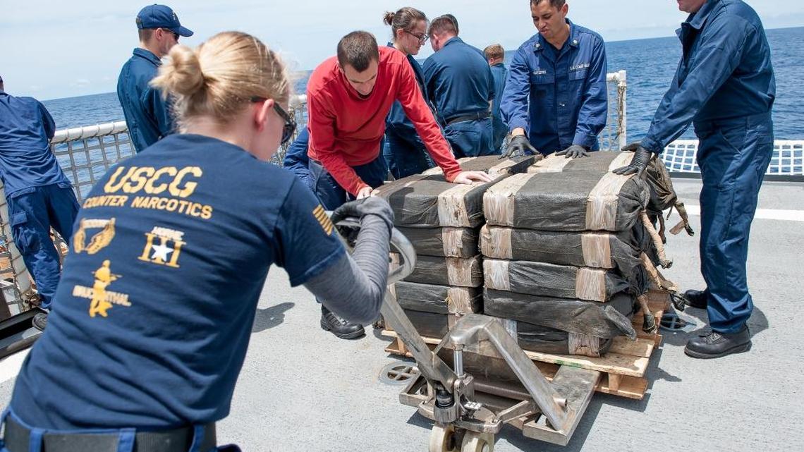 In this July 19, 2015 photo released by the U.S. Coast Guard, crew members secure cocaine bales from a self-propelled semi-submersible interdicted in international waters. Officials say drug traffickers are increasingly turning to the sea to get their loads to U.S. markets.