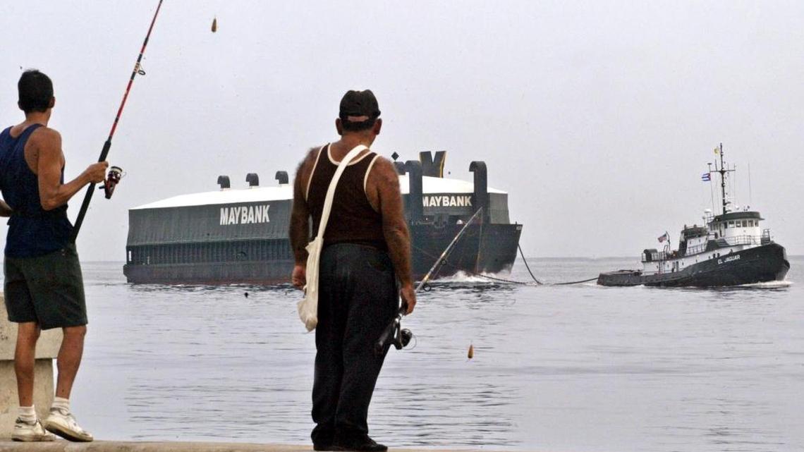 Cuban fishermen look at the U.S. Maybank Shipping Company vessel, Helen III arriving to Havana harbor, 11 July 2003, with 1,5 million dollars cargo in paper and wood from Alabama. This is the first time in 43 years that a ship with U.S. flag arrives to Cuba