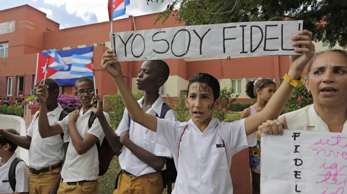 Cuban school children wait for the passage of Fidel Castro's ashes outside a clinic on the route to the Moncada Barracks, in Santiago de Cuba on Saturday, December 3, 2016.