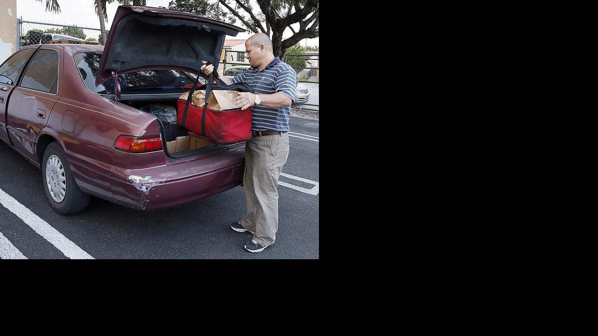 
Dr. Duvier Gomez, who recently arrived from Cuba, loads his car with a delivery bag from the Pasta Factory. Gomez works as a driver on weekends to support his family while studying to get his medical title during the week.
