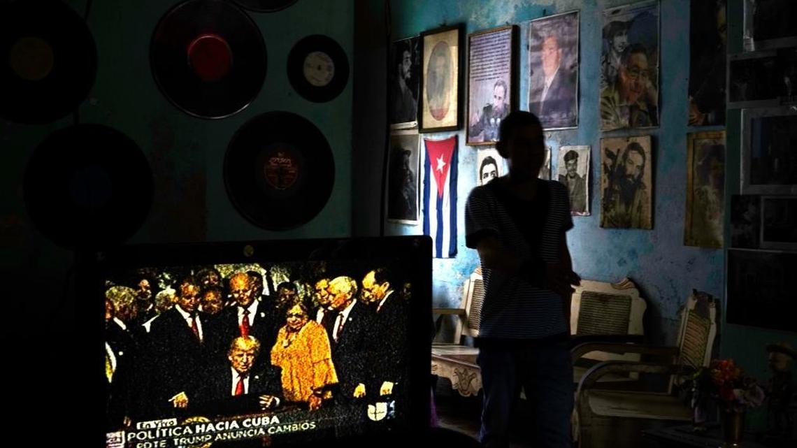 In this June 16, 2017, file photo, a Havana man walks past a television set showing President Donald Trump signing a memorandum on his new Cuba policy, in a living room festooned with images of Cuban leaders.
