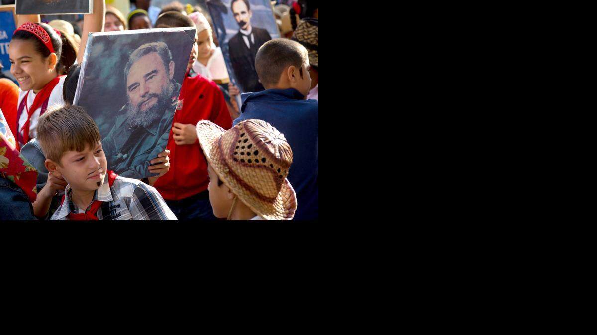 
A child holds an image of Fidel Castro during a lull in a caravan tribute marking the 56th anniversary of the original street party that greeted a triumphant Castro and his rebel army, in Regla, Cuba, Thursday, Jan. 8, 2015. Castro and his rebels arrived in Havana via caravan on the first week of January 1959, after toppling dictator Fulgencio Batista. The revolutionary leader and former president has not spoken publicly on the historic Dec. 17th US-Cuba detente. 
