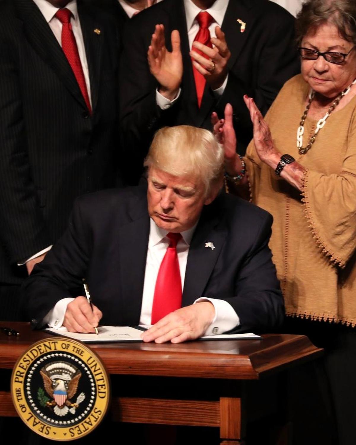 President Donald Trump signs policy changes he is making toward Cuba at the Manuel Artime Theater in the Little Havana neighborhood on June 16, 2017.