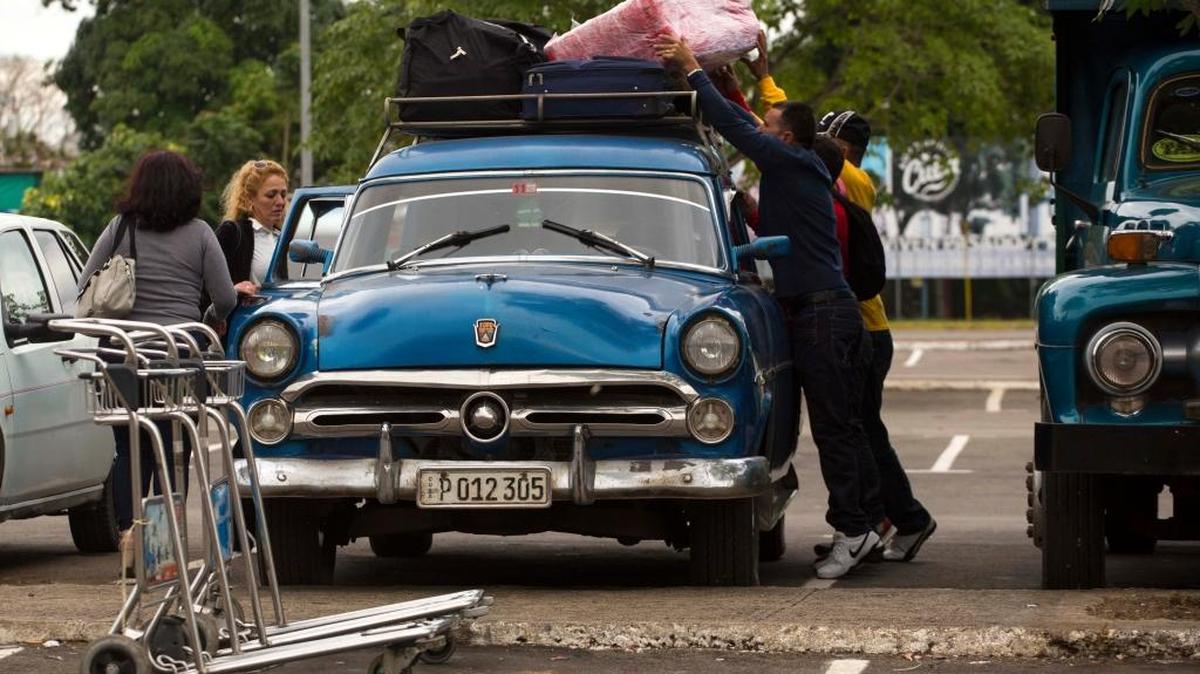 Men load suitcases on the top of a car after travelers arrived to the Jose Marti International Airport in Havana, Cuba.
