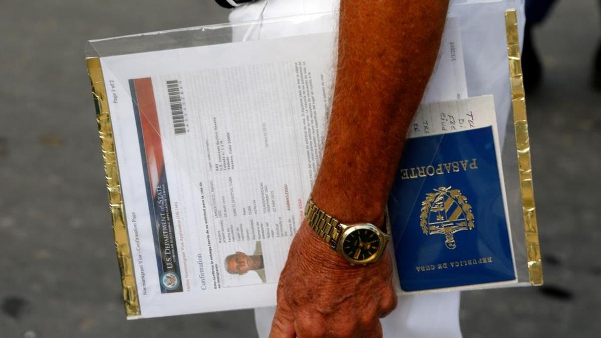 A man applying for a U.S. visa holds his U.S. Department of State forms and Cuban passport as he waits in line outside the U.S. diplomatic mission in Havana.