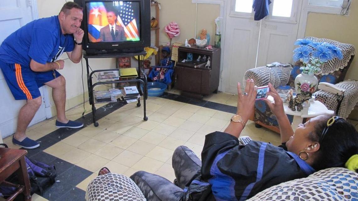 María Lastres snaps a cellphone picture of her husband, Jesús Magán, as they watch President Obama speak from their Havana apartment.