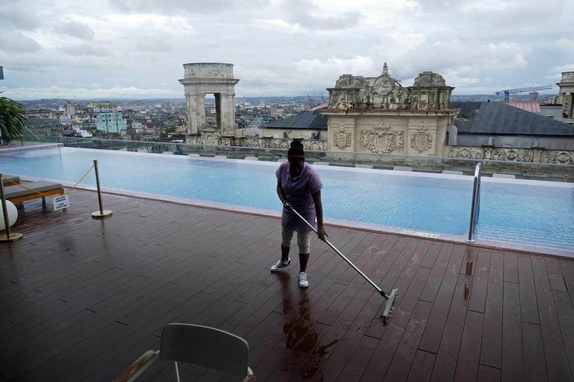 A worker at the new five-star hotel, Gran Hotel Manzana Kempinski, in Old Havana, sweeps the rooftop pool deck following a heavy downpour. The Kempinski is one of the Cuban hotels now off-limits for U.S. travelers.