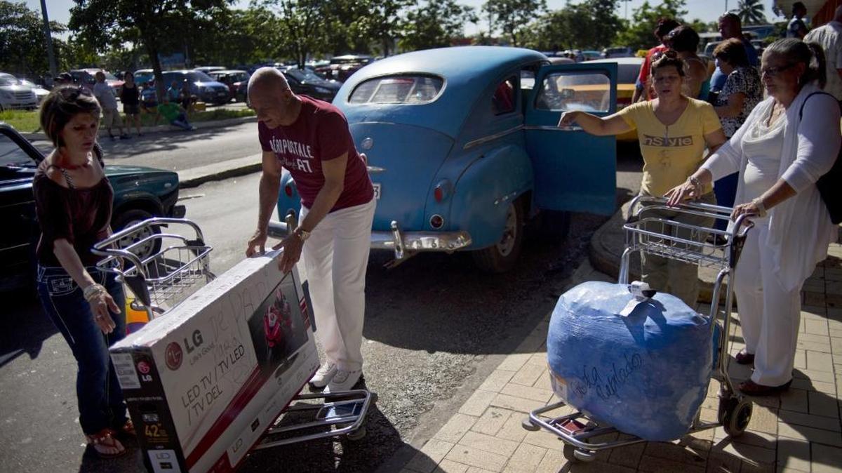 A man prepares to lift a large TV to a private taxicab as he helps a traveler who arrived from the U.S. at José Martí International Airport in Havana, Cuba.