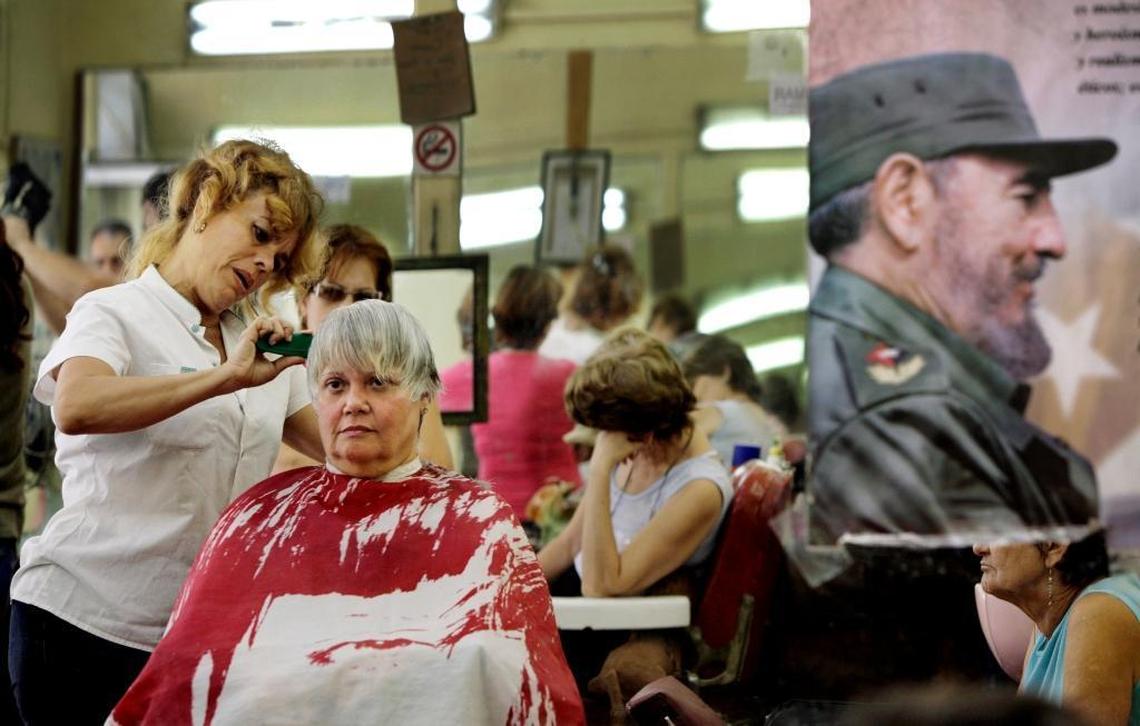 Josefina Hernandez cuts a customer's hair next to a poster of Fidel Castro hanging in a barber shop in Old Havana in 2010. That was the year Cuba began turning over some formerly state-run barber shops and hair salons to the employees who work in them.