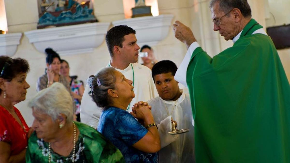 In this June 19, 2016 photo, Havana Archbishop Juan de la Caridad García Rodríguez administers communion to parishioners in Saint John the Baptist church in Jaruco, Cuba.
