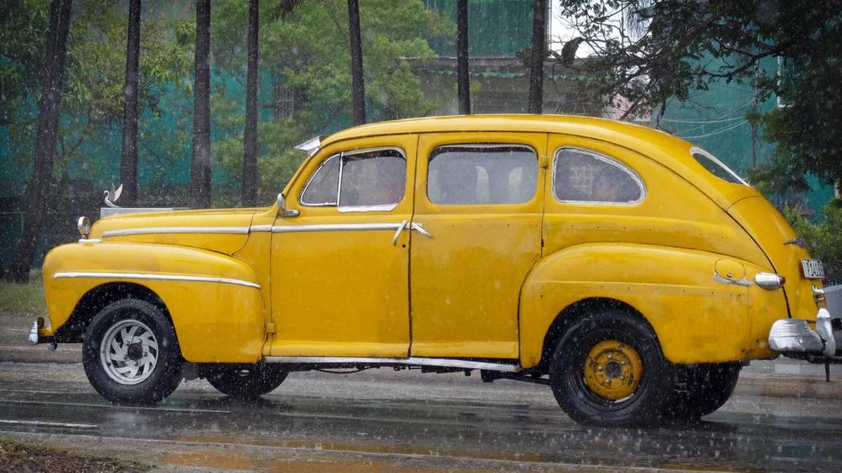 A car makes its way through the wet streets of Havana on a rainy, Friday afternoon in 2015.