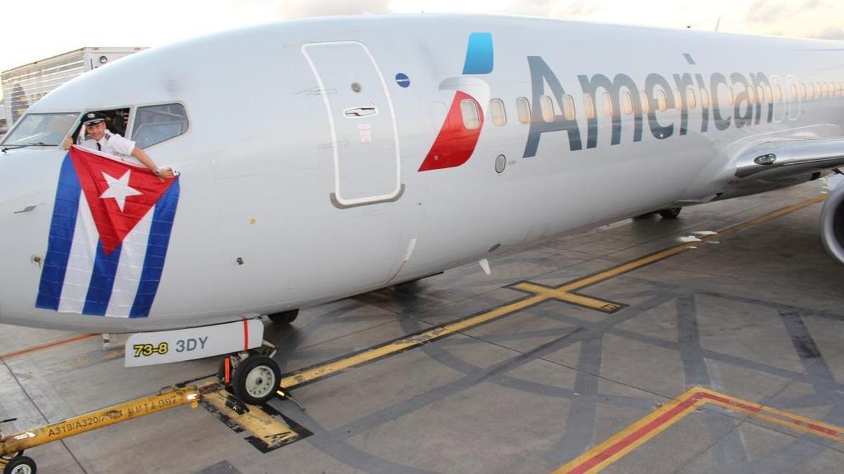 American Airlines chief pilot Kevin Mase drapes a Cuban flag from a Boeing 737 on Dec. 16, 2015, the day the United States and Cuba announced an agreement on restoring commercial air service between the two countries. Now AA is awaiting final route approval from Cuba.